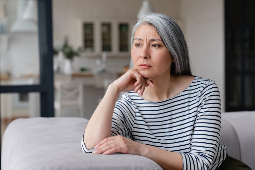 Woman sitting in living room with a worried face expression.